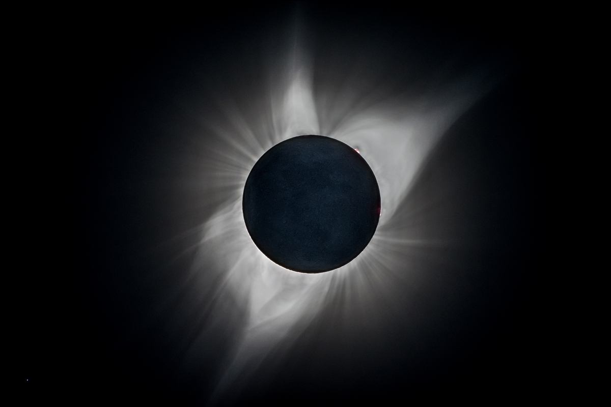 Total solar eclipse with the corona streaming around the dark moon